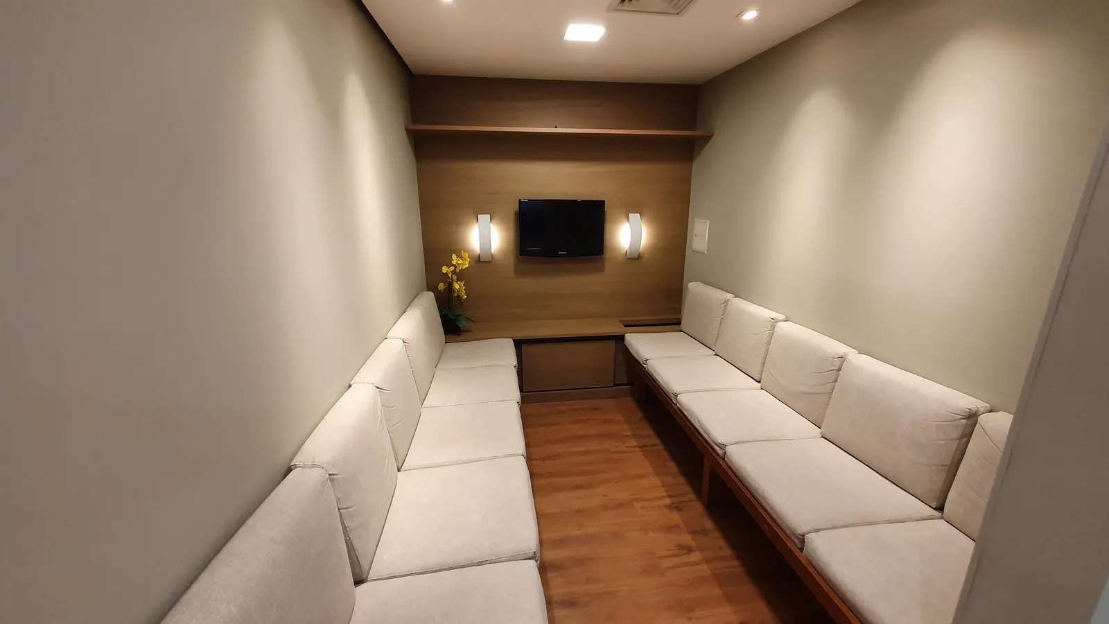 Sala de espera da Otológica, com sofás claros e painel de madeira